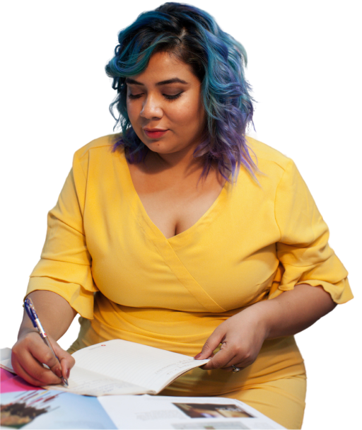 Woman in a yellow dress with blue hair is writing in a notebook.
