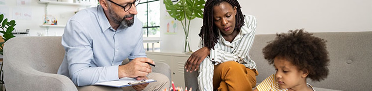 Woman and man helping a kid with coloring